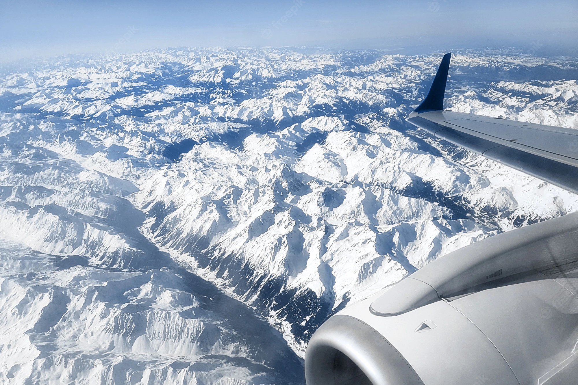 view-from-airplane-window-snow-capped-peaks-alpine-mountains-engine-aircraft_94065-298